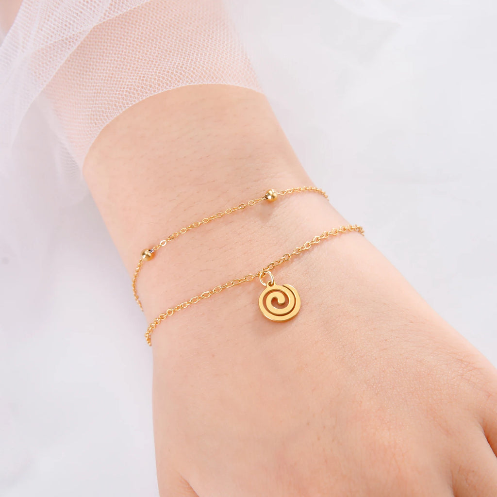 Forgyldt armbånd med lille spiralvedhæng i guld