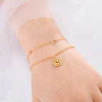 Forgyldt armbånd med lille spiralvedhæng i guld