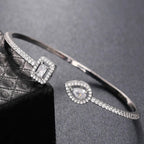 Pulseira aberta pavé de strass e pedra de cristal em forma de gota de água prateado e branco